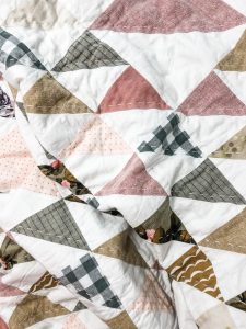Hand quilted quilt made of Half Square using Liquid Starch triangles in earth tones and florals