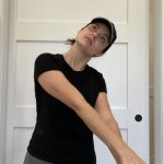 Elizabeth Chappell in a black hat and black shirt stretching her arms