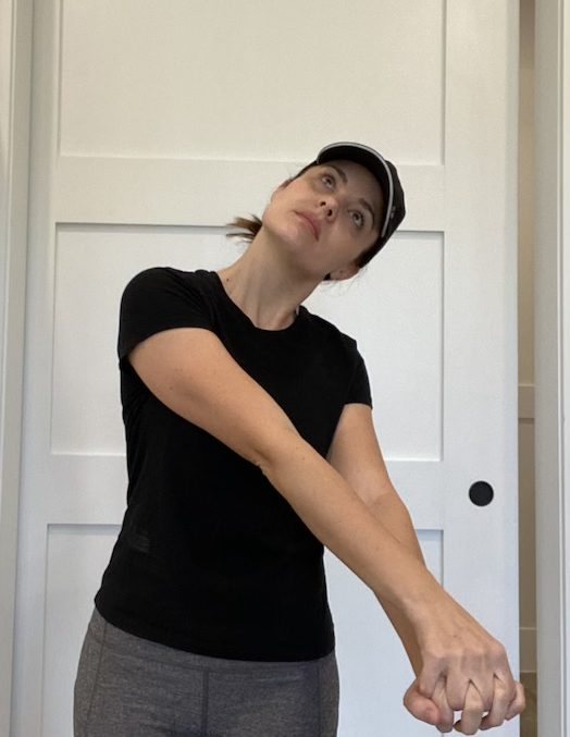 Elizabeth Chappell in a black hat and black shirt stretching her arms