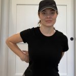 Elizabeth Chappell in a black hat and black shirt stretching her arms