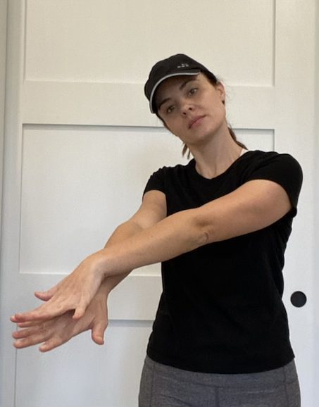 Elizabeth Chappell in a black hat and black shirt stretching her neck