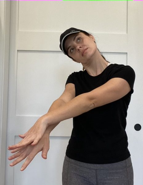 Elizabeth Chappell in a black hat and black shirt stretching her neck