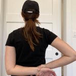 Elizabeth Chappell in a black hat and black shirt stretching her arms