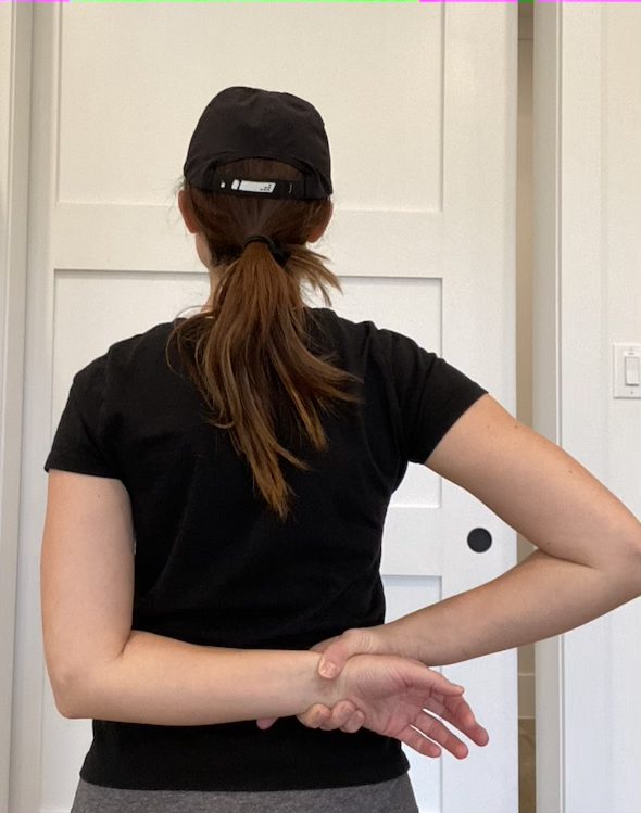 Elizabeth Chappell in a black hat and black shirt stretching her arms