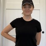 Elizabeth Chappell in a black hat and black shirt stretching her arms