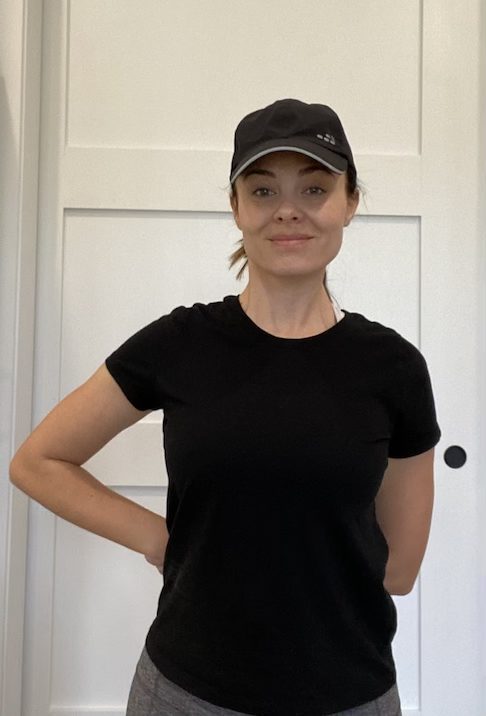 Elizabeth Chappell in a black hat and black shirt stretching her arms