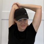 Elizabeth Chappell in a black hat and black shirt stretching her arms