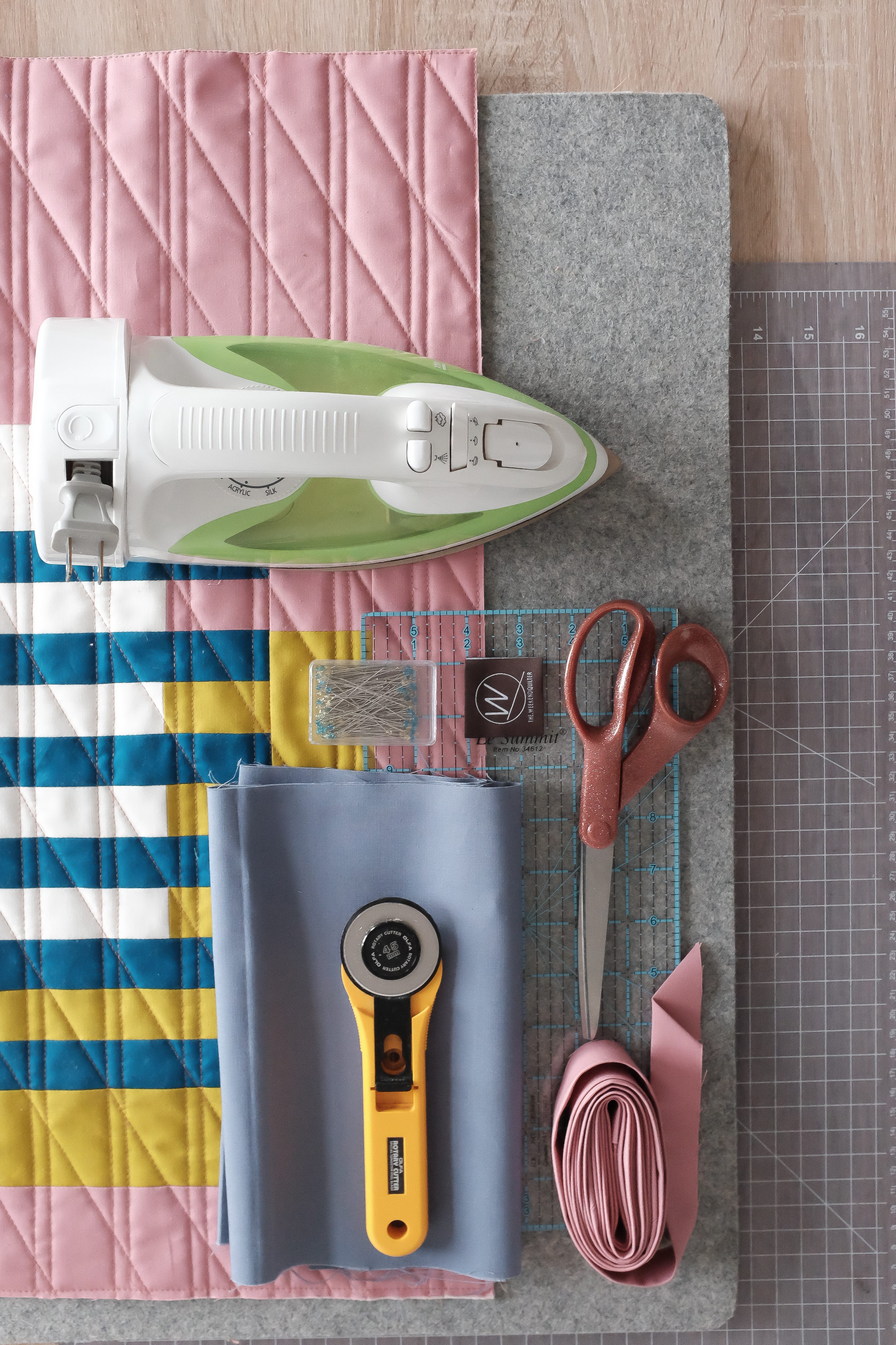 An iron, scissors, rotary cutter, fabric, and a pressing mat