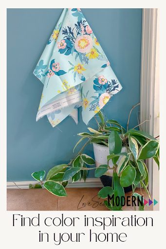 Blue and pink floral fabric on blue wall with green house plant for color palette inspiration