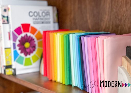 Color wheel book with folded brightly colored fabrics lined up on a shelf