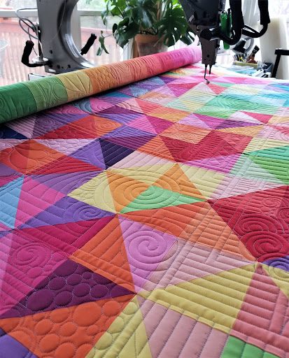 Anything by Krista Withers quilting design over reds, pinks, oranges purples, yellows...
