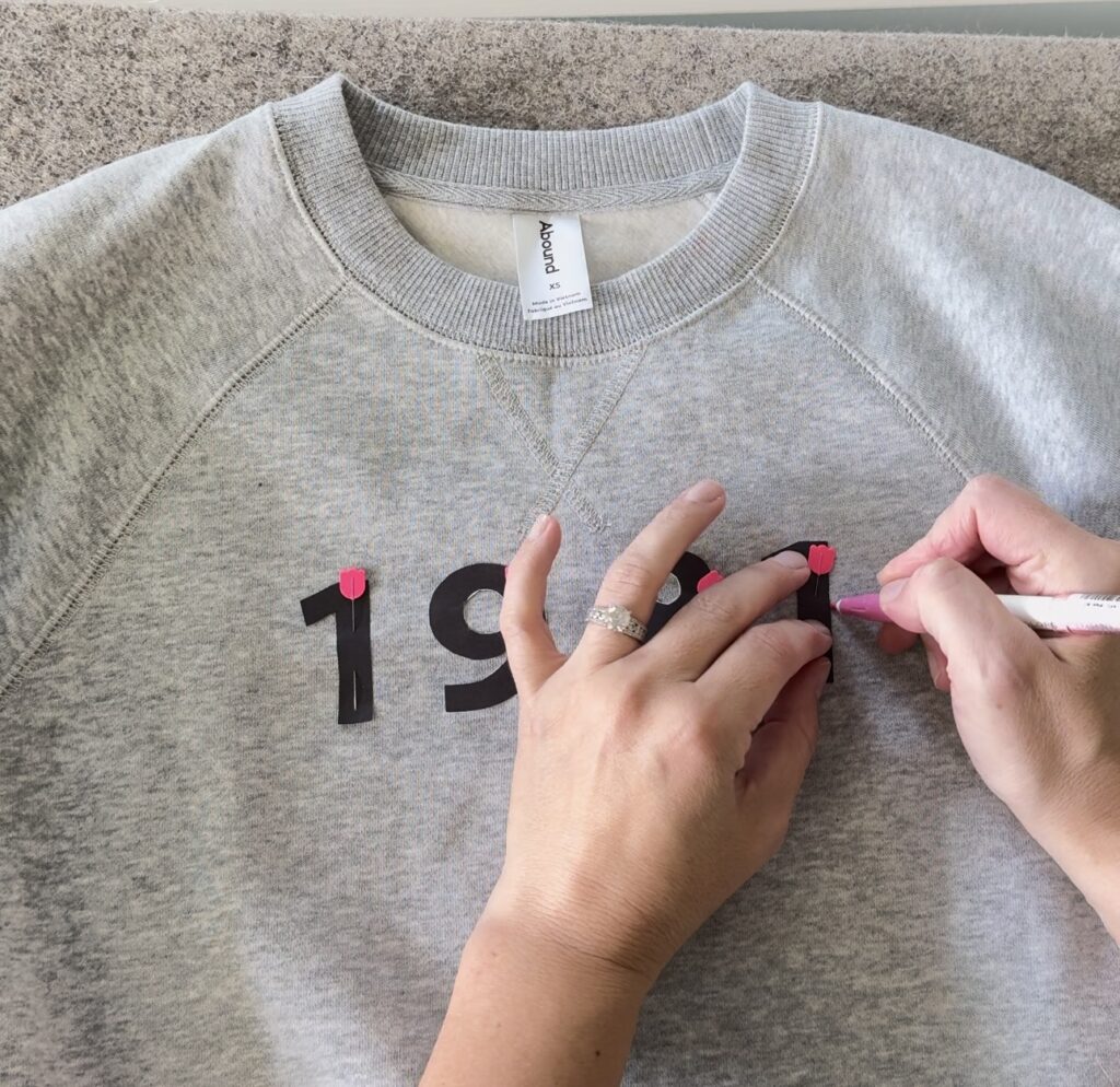 grey sweatshirt with '1981' being traced on it