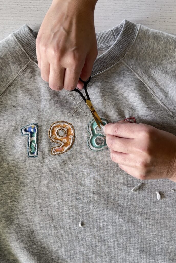 the numbers 198 in blue, yellow and green on a grey sweatshirt