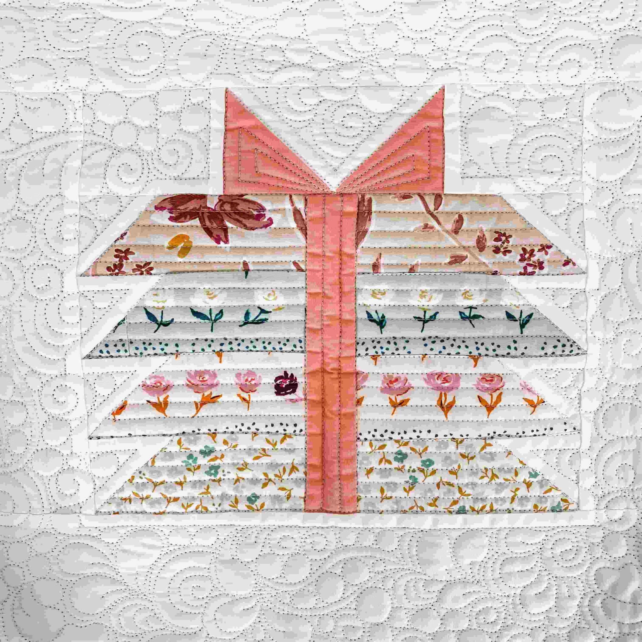 bundle of joy quilt block with a pink ribbon and blue and pink floral fabric