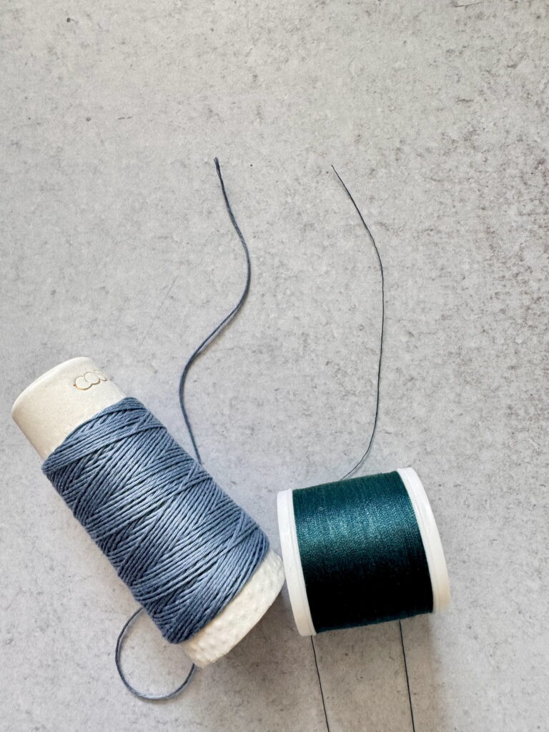 Side-by-side comparison of thick blue quilting thread and thinner green thread, demonstrating the difference in thread weight.
