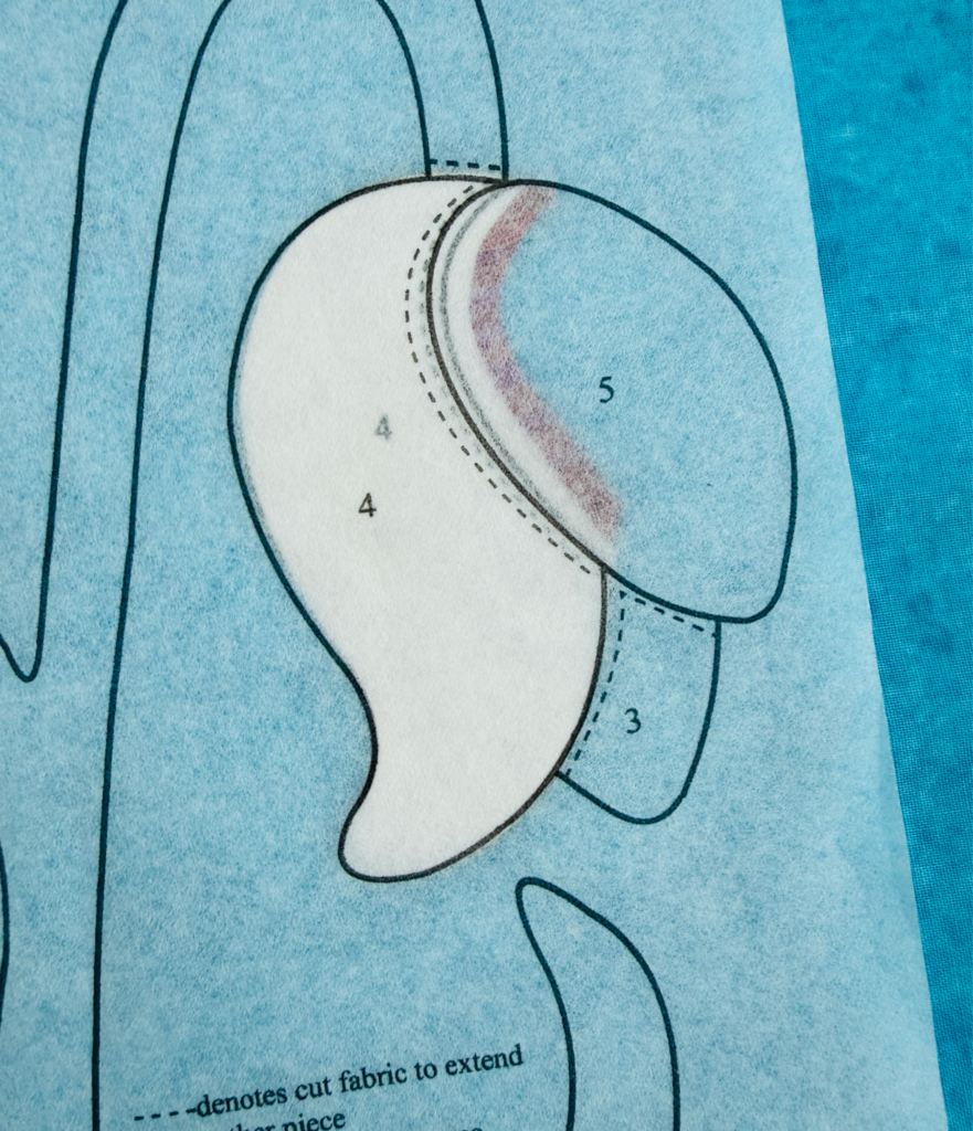 Thin line of glue applied to the seam allowance of a fabric appliqué shape before turning the edge.