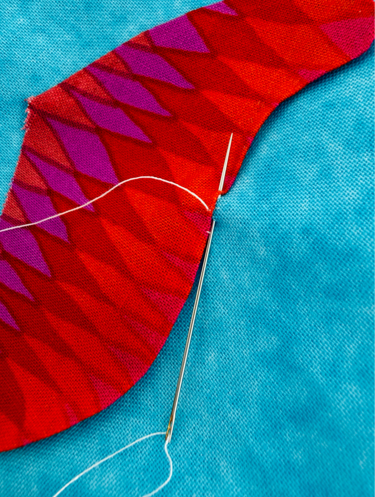 Hand stitching a smooth inside curve on a turned-edge appliqué shape with matching thread.