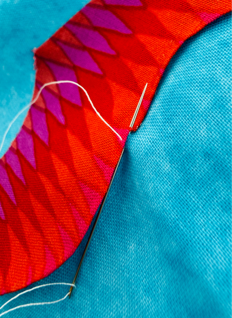 Close-up of hand stitching around the outside curve of a turned-edge appliqué shape.