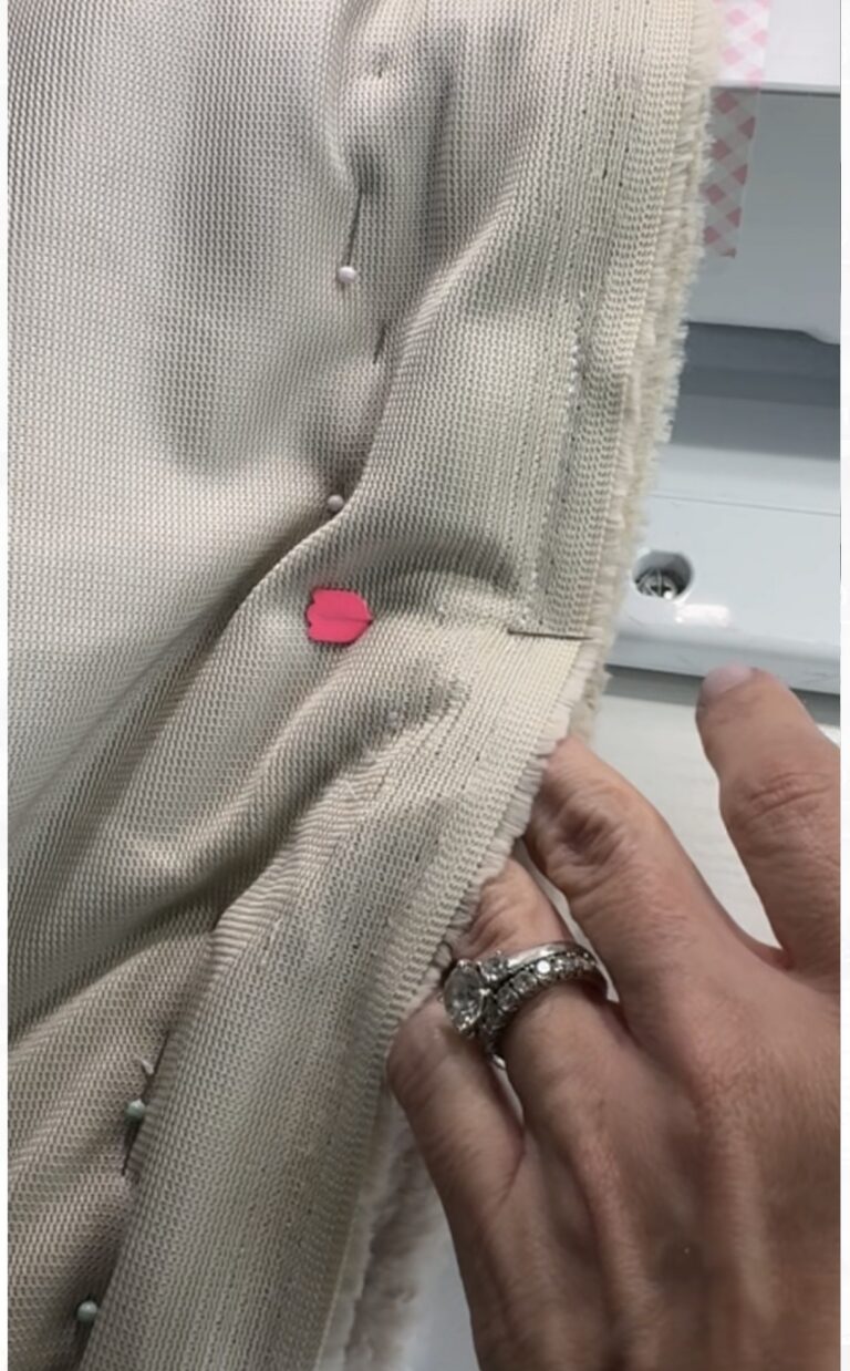 Close up of a hand checking the seam allowance on a cuddle cut whole cloth quilt