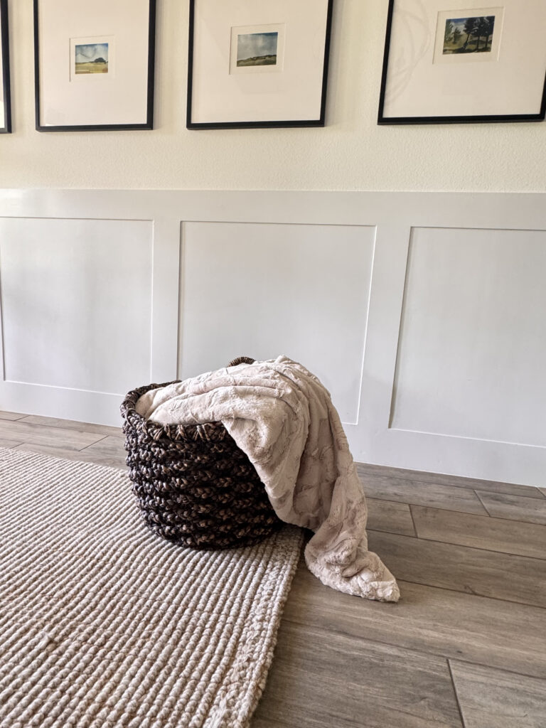 DIY cuddle cut whole cloth quilt folded in a woven basket in a farmhouse style entryway