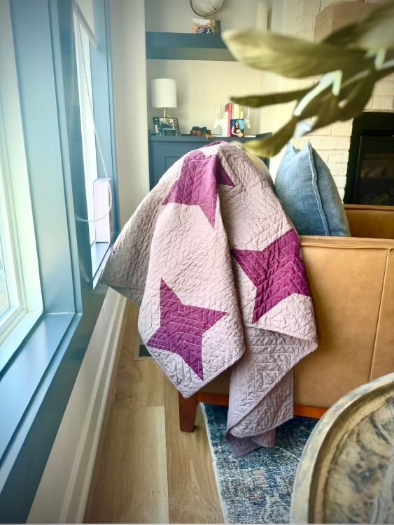 Finished mauve quilted ruana with burgundy stars draped over a chair