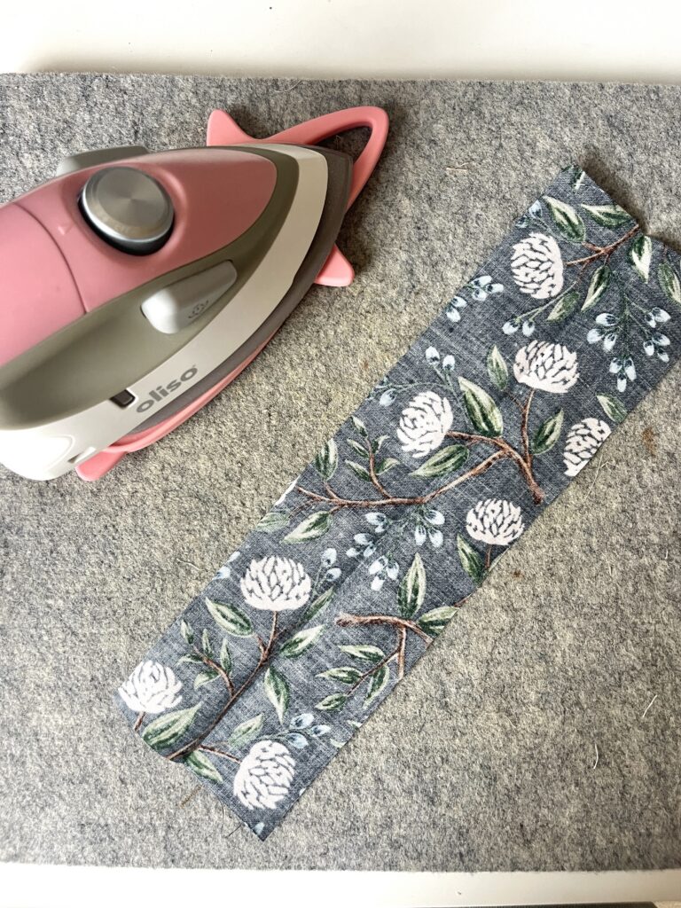 Fabric strip placed wrong side up on a wool pressing mat, ready to fold