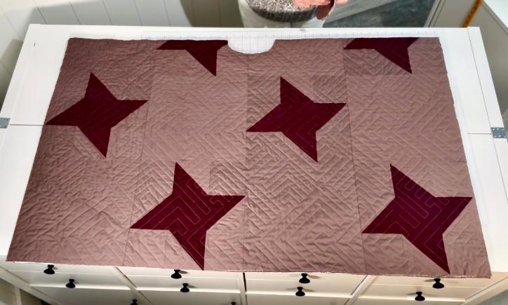 Star quilt laid flat on a cutting table with a curved neckline and front opening