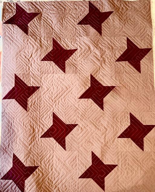 Mauve and burgundy star quilt with geometric quilting before being made into a ruana